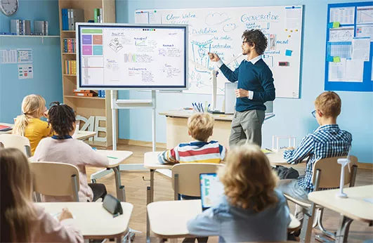 A teacher using an audiovisual board to give a lesson to his students