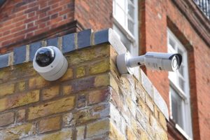 A CCTV security camera and a motion sensor attached to a brick wall