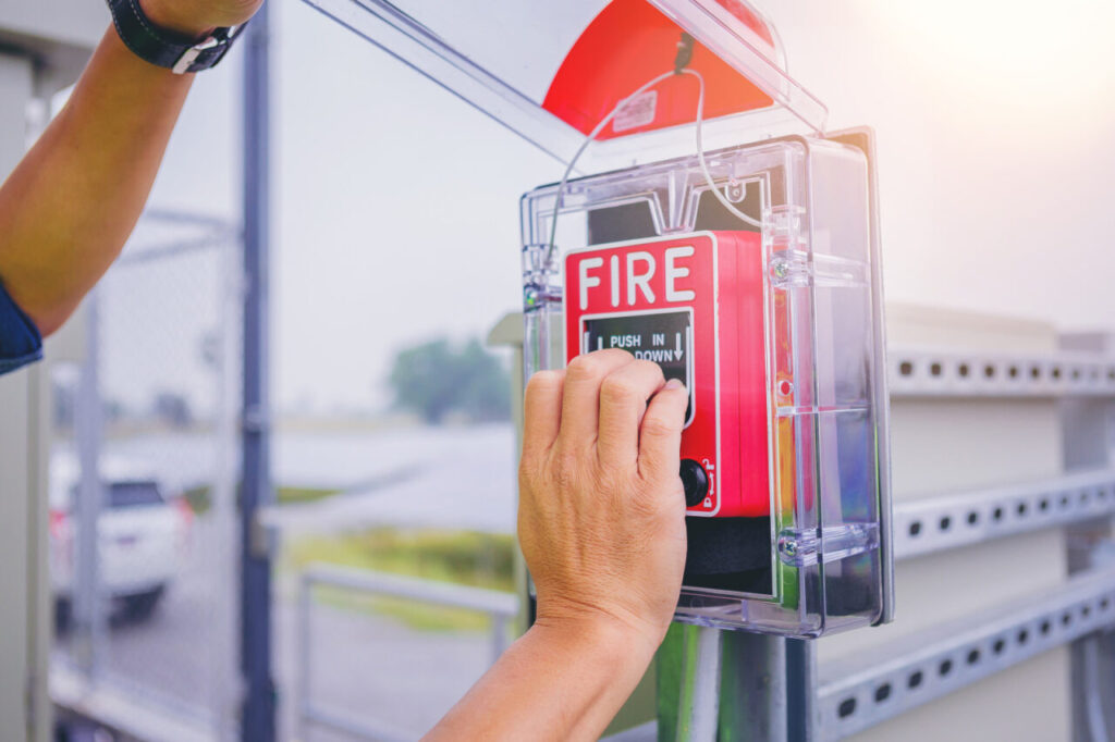  hands open and pushing fire alarm switch